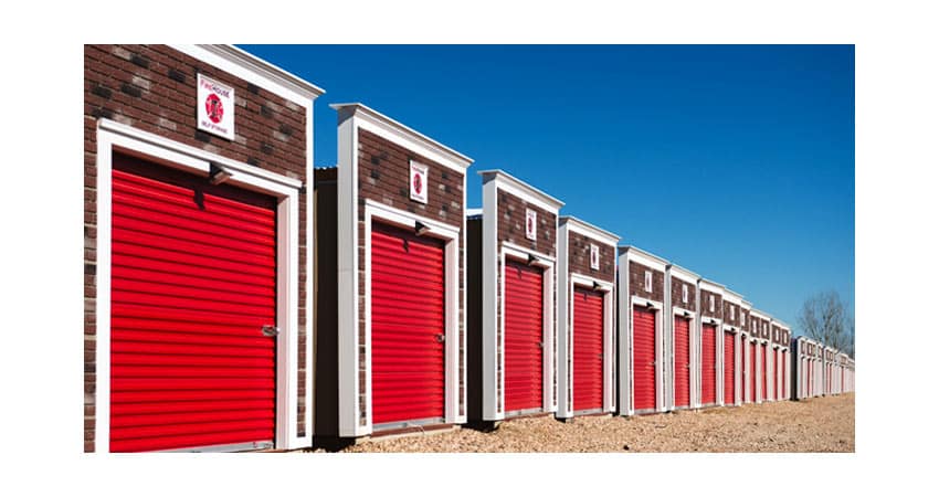 Picture of brick storage unit buildings with red garage doors.