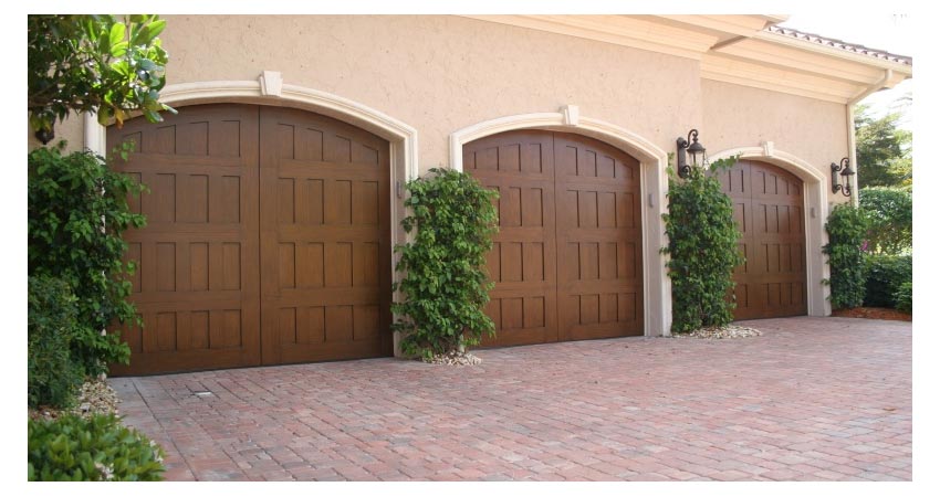 Picture of a tan house with three brown garage doors.
