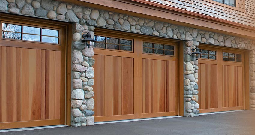 Picture of a stone house with three wooden garage doors.
