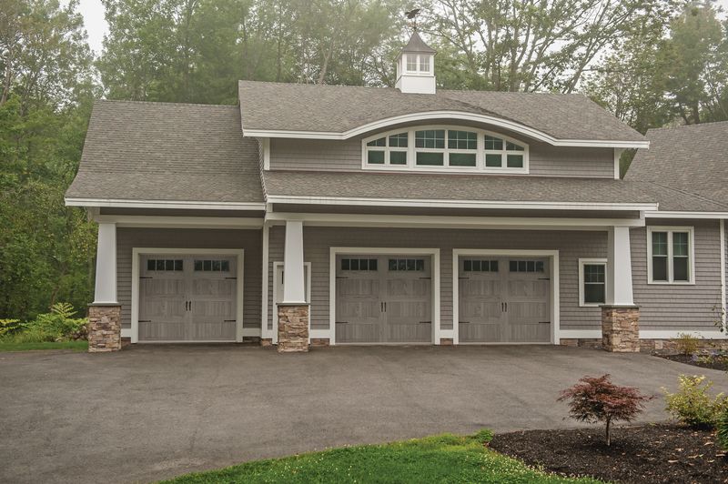 Picture of a grey house with gray wooden garage doors.