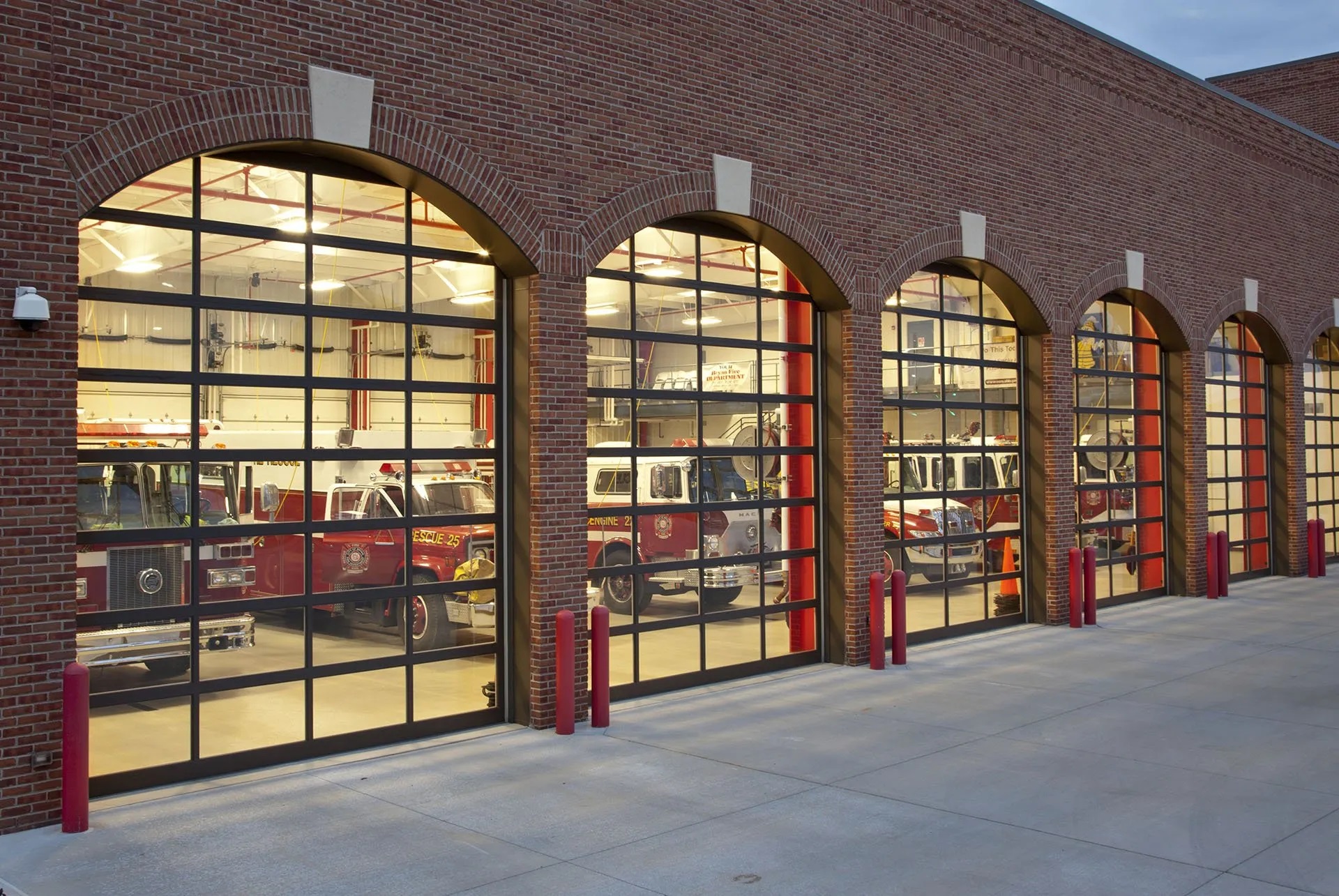 Picture of a red brick fire station with see through garage doors.